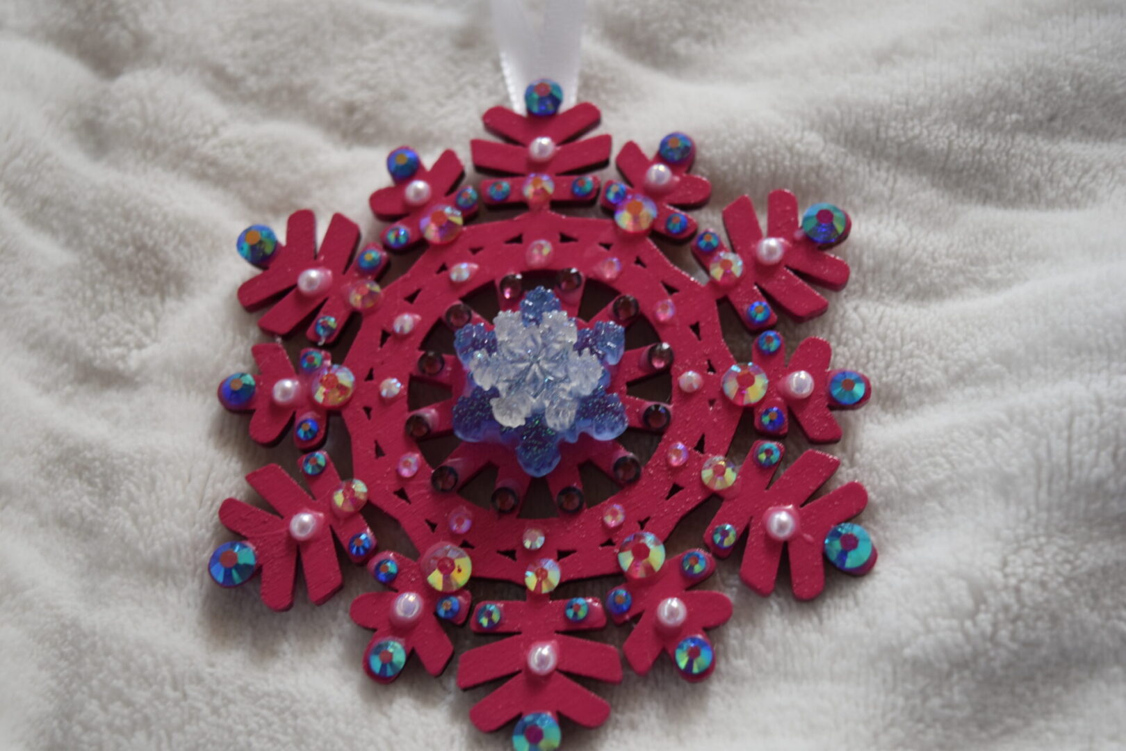 A red and blue snowflake ornament on white fabric.