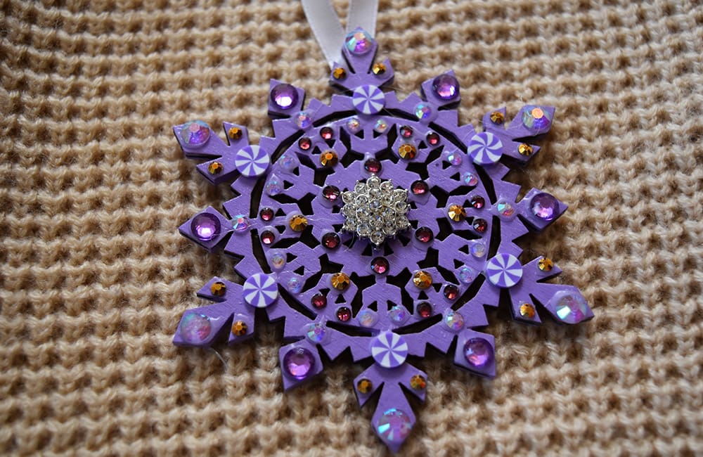 A purple snowflake ornament with jewels on it.