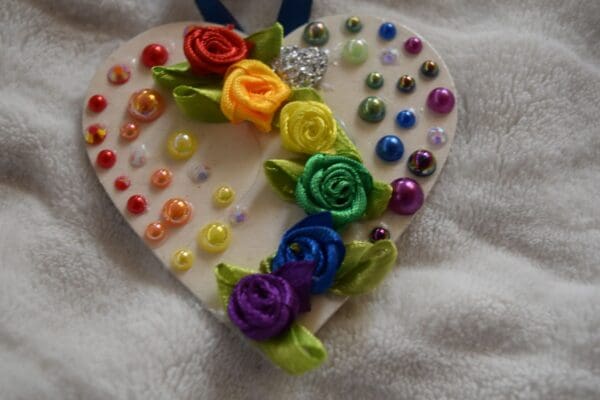 A heart shaped ornament with rainbow roses and beads.