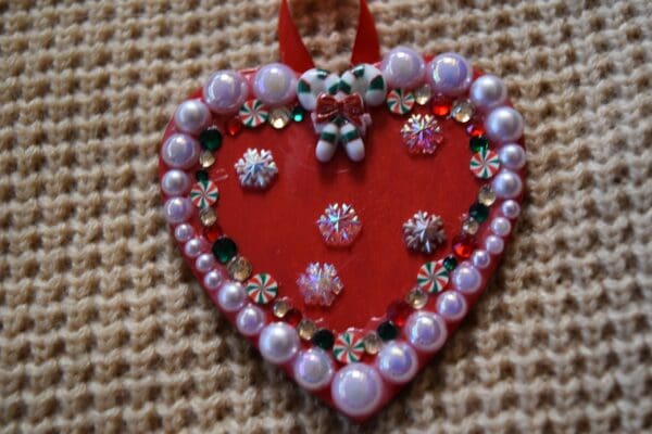 A red heart with pearls and bows on it.