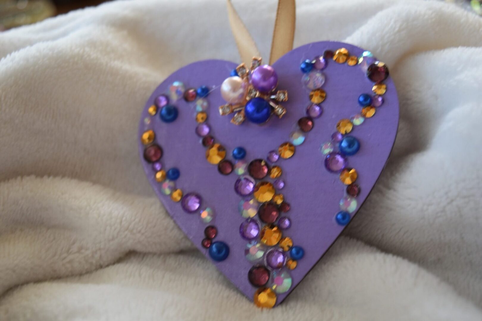 A purple heart with beads and pearls on top of it.