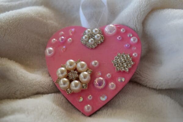 A pink heart with pearls and jewels on it.