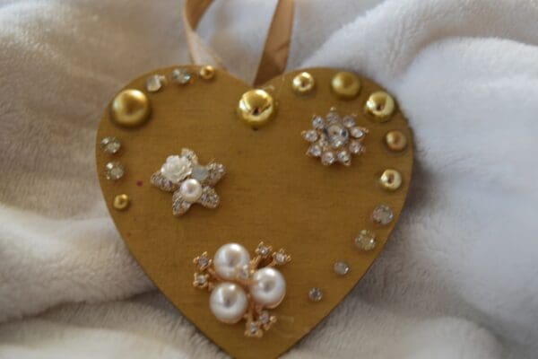 A heart shaped ornament with gold and pearls.