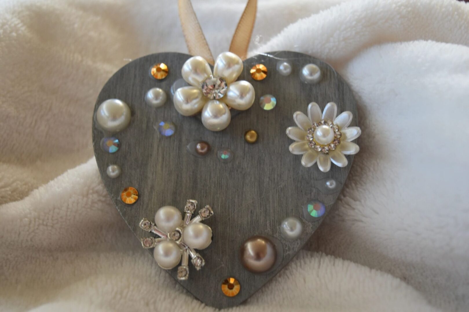 A heart shaped ornament with pearls and flowers.