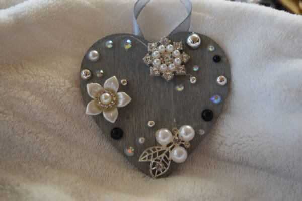 A heart shaped ornament with some flowers and pearls