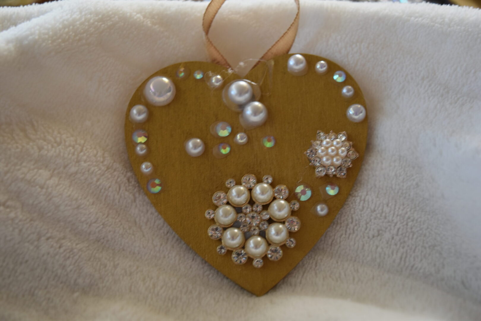 A heart shaped ornament with pearls and rhinestones.