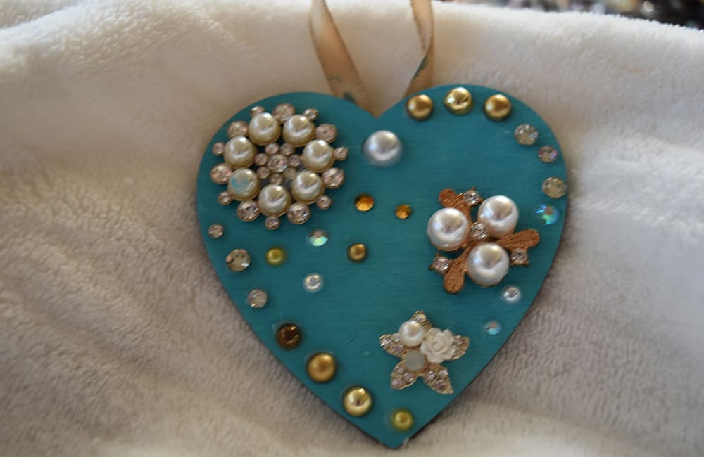 A heart shaped ornament with pearls and sequins.