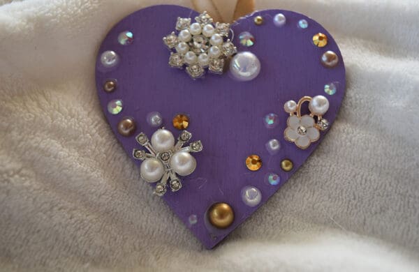 A purple heart with jewels and pearls on it.