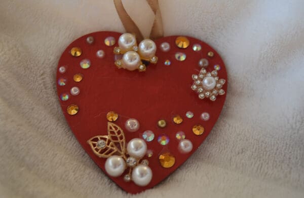 A red heart with pearls and gold embellishments.