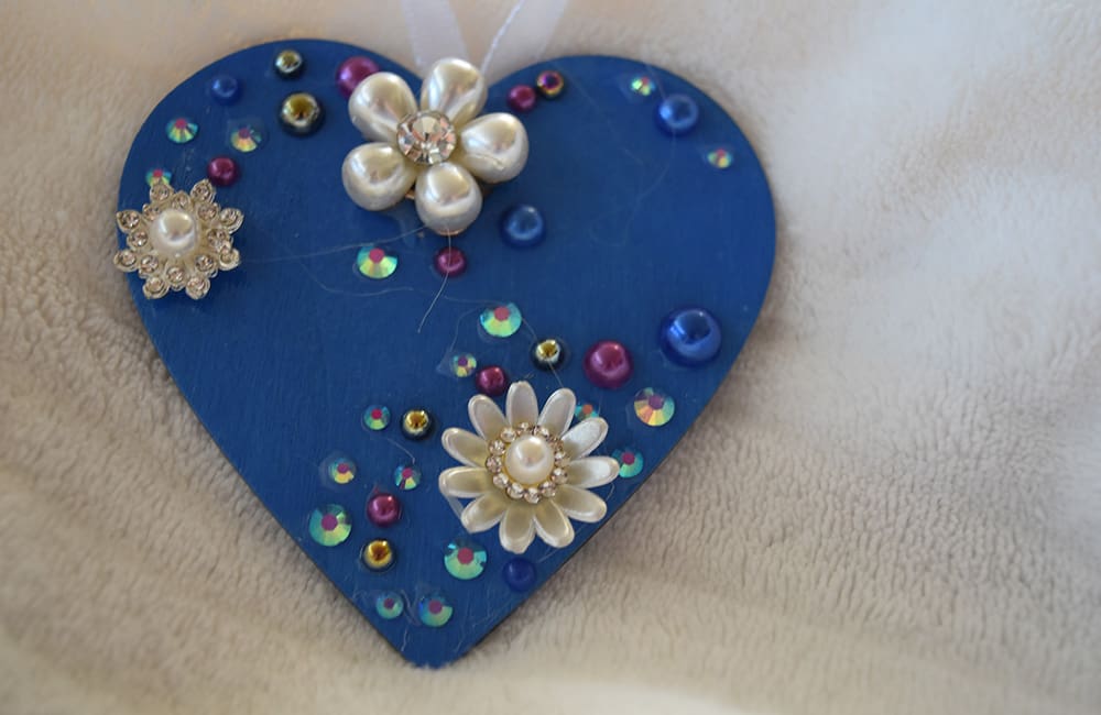 A blue heart with flowers and pearls on it.