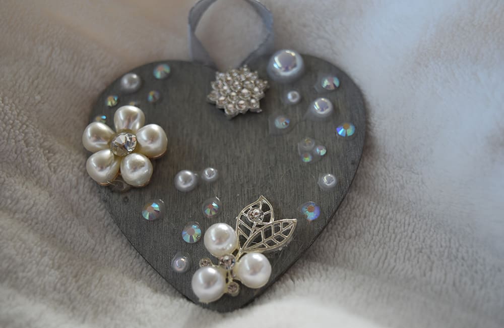 A heart shaped ornament with pearls and jewels.