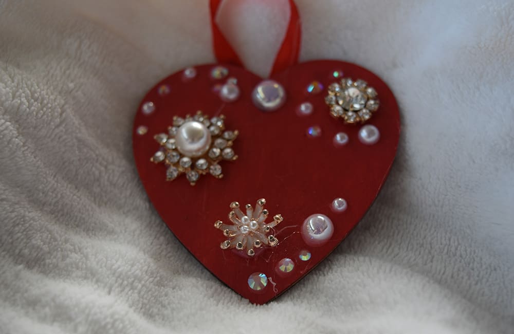 A red heart with some white pearls and jewels on it