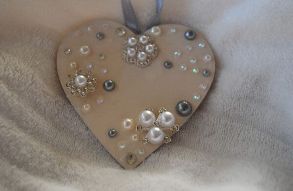 A heart shaped ornament with some beads and rhinestones