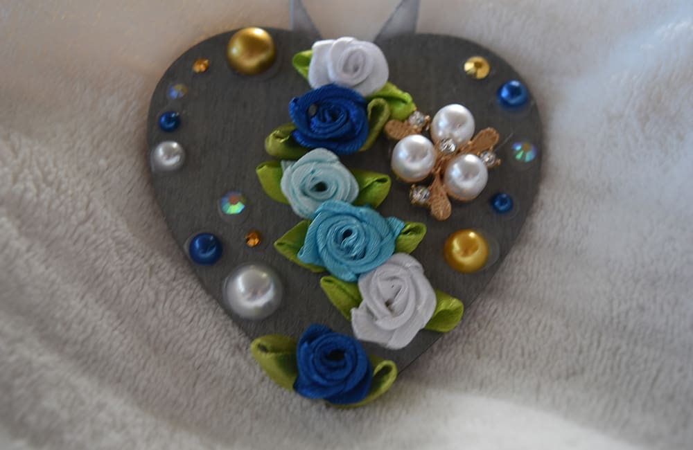 A heart shaped ornament with flowers and pearls.