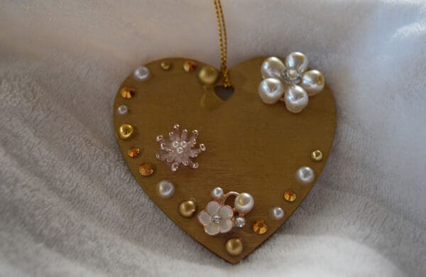 A heart shaped ornament with pearls and rhinestones.