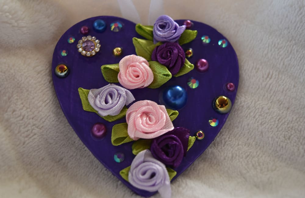 A purple heart with flowers and jewels on it.