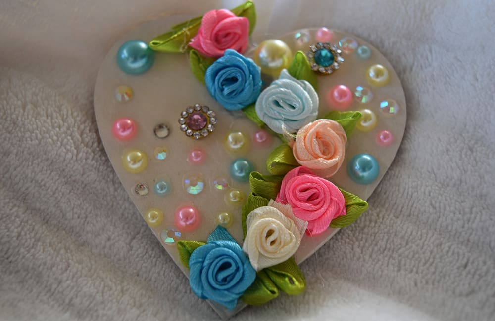 A heart shaped decoration with flowers and pearls.