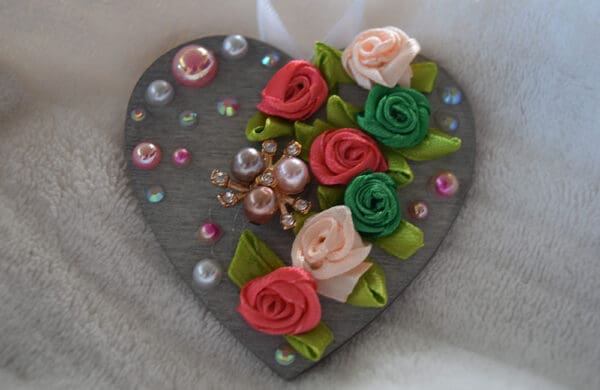 A heart shaped decoration with flowers and pearls.