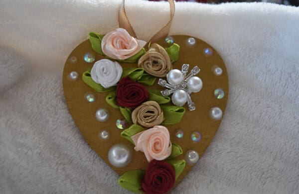 A heart shaped ornament with flowers and pearls.