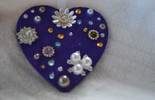 A heart shaped ornament with jewels and pearls.