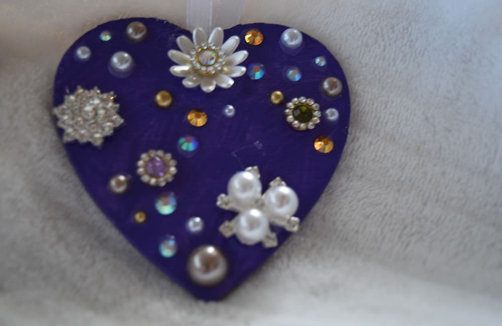 A heart shaped ornament with jewels and pearls.