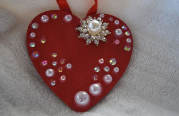 A red heart with white and pink pearls on it.