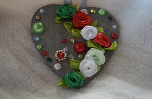 A heart shaped ornament with flowers and buttons.