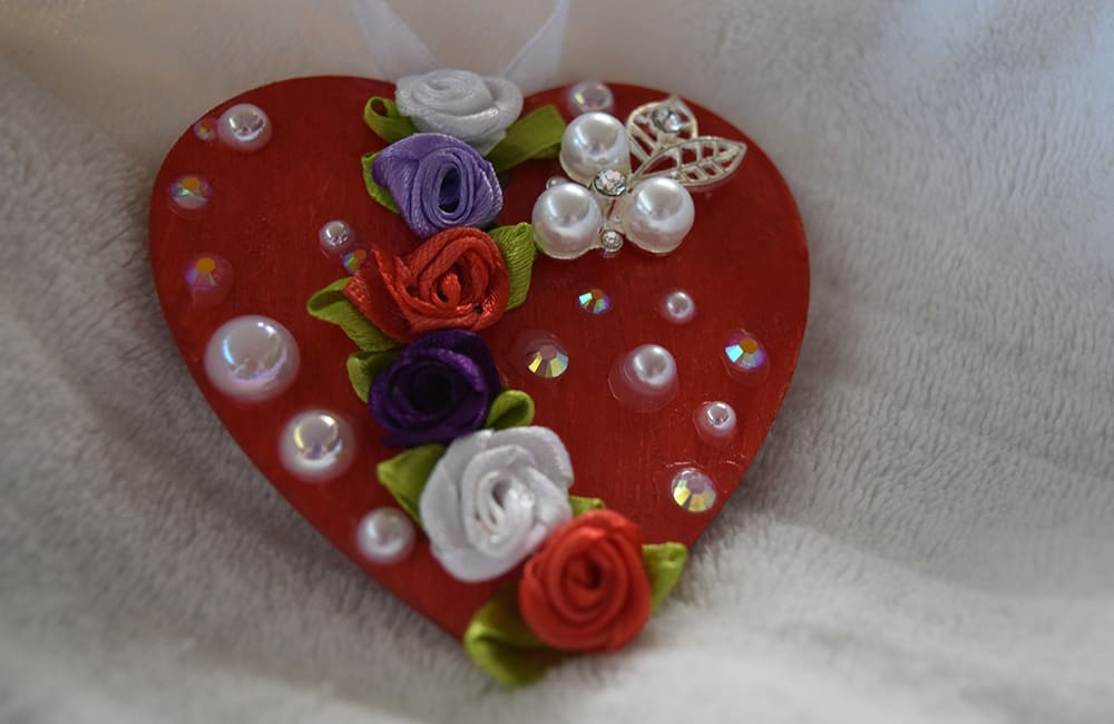 A heart shaped ornament with flowers and pearls.