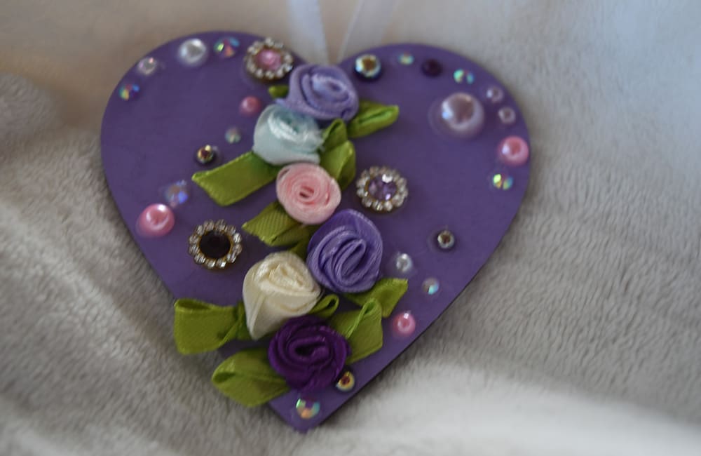 A purple heart with flowers and jewels on it.