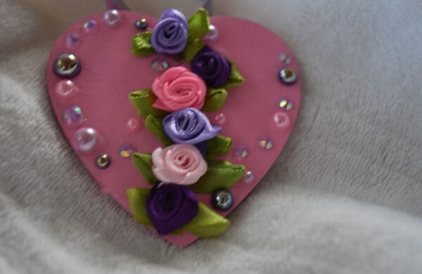 A pink heart with purple and pink roses on it.