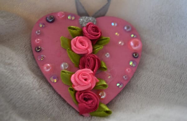 A pink heart with roses and green leaves.