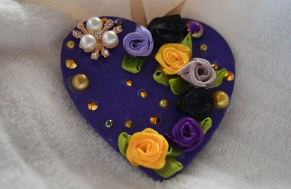 A purple heart with flowers and pearls on it.