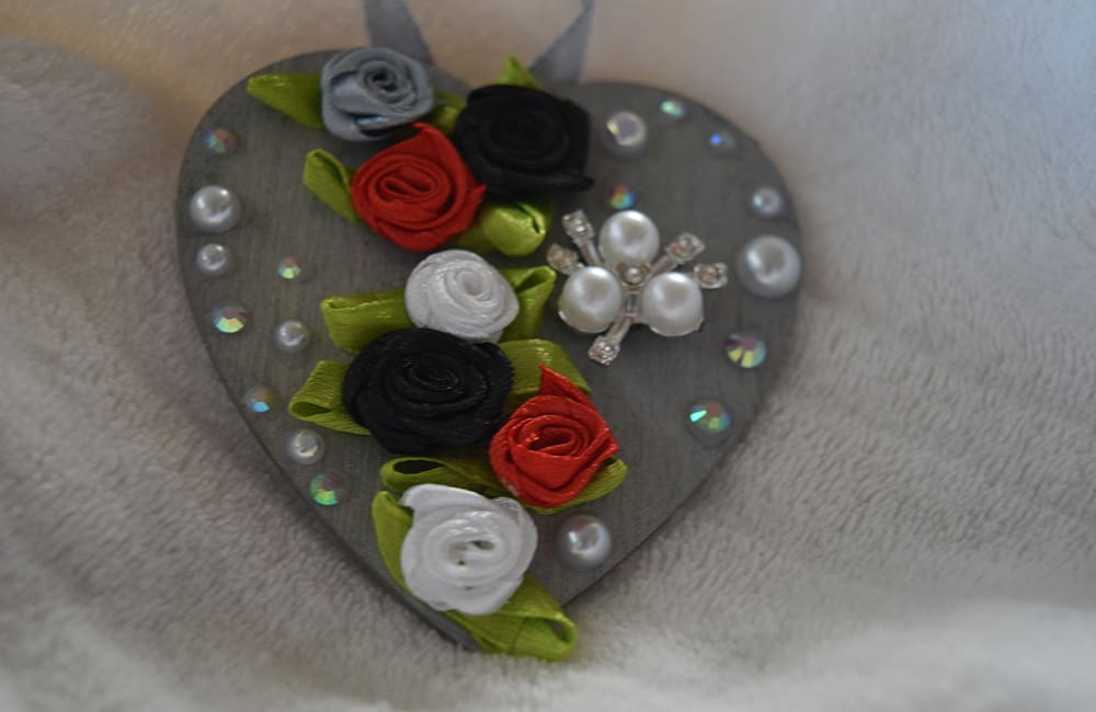 A heart shaped ornament with flowers and pearls.