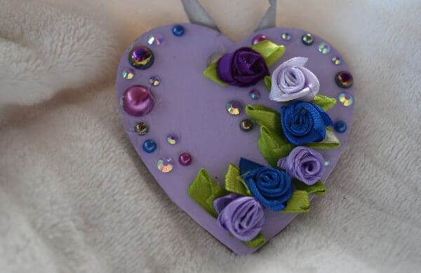 A purple heart with flowers and jewels on it.