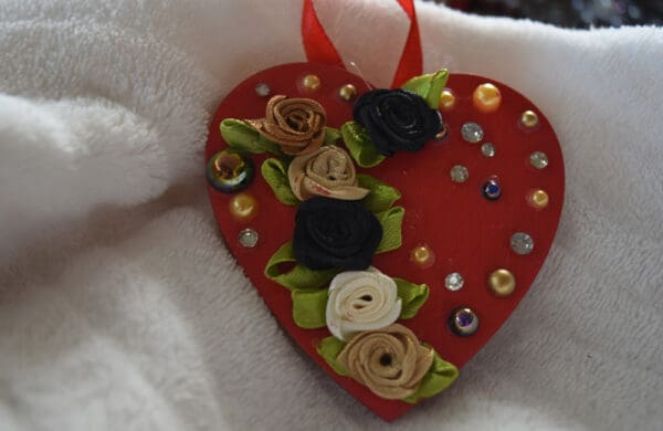 A red heart with flowers and beads on it.