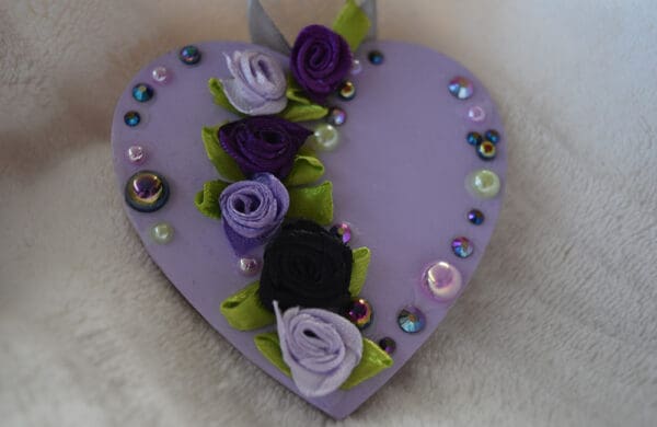 A purple heart with flowers and jewels on it.