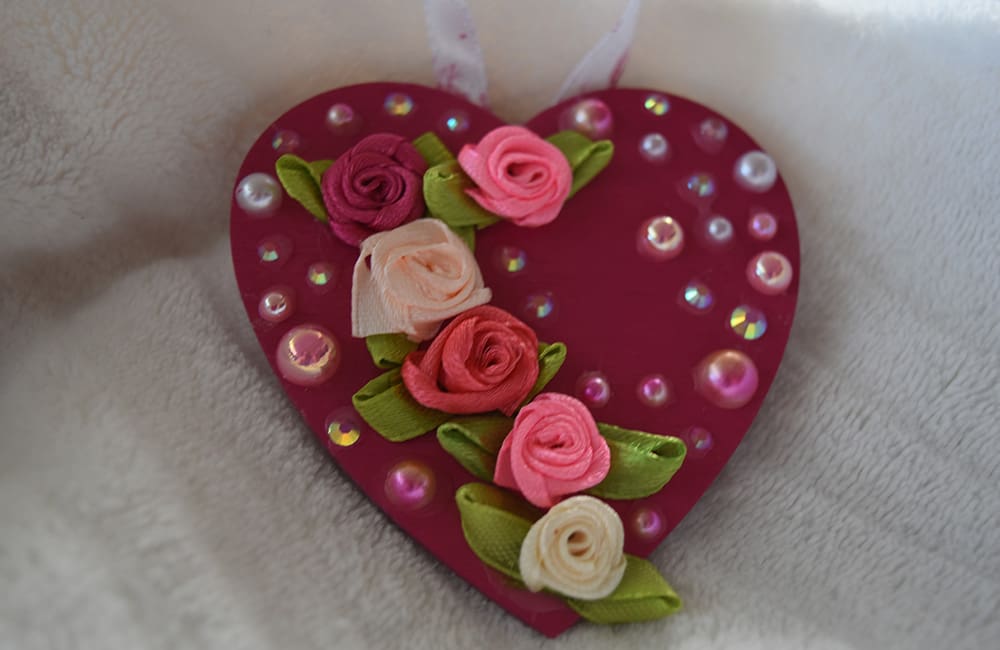 A heart shaped ornament with flowers and beads.