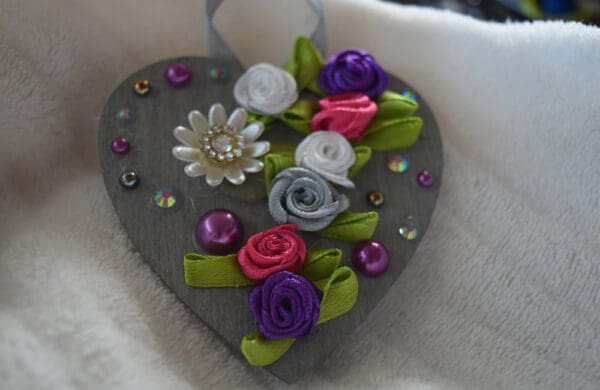 A heart shaped ornament with flowers and beads.