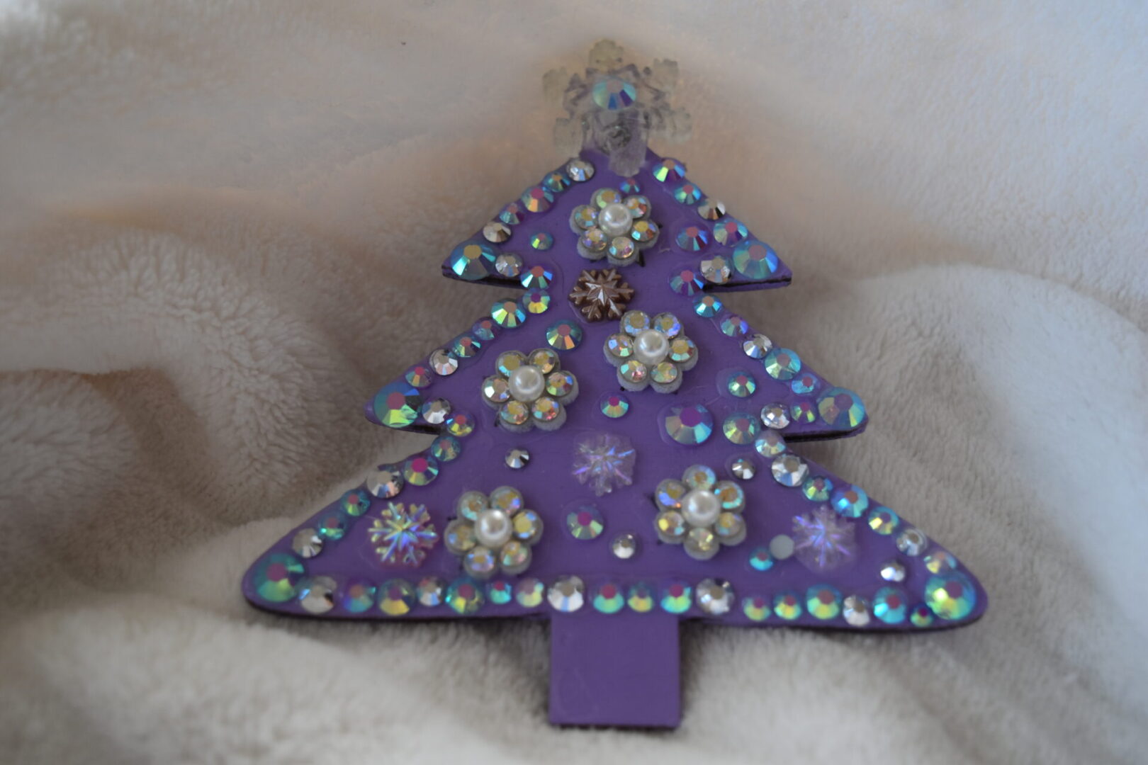 A purple christmas tree with jewels on top of it.