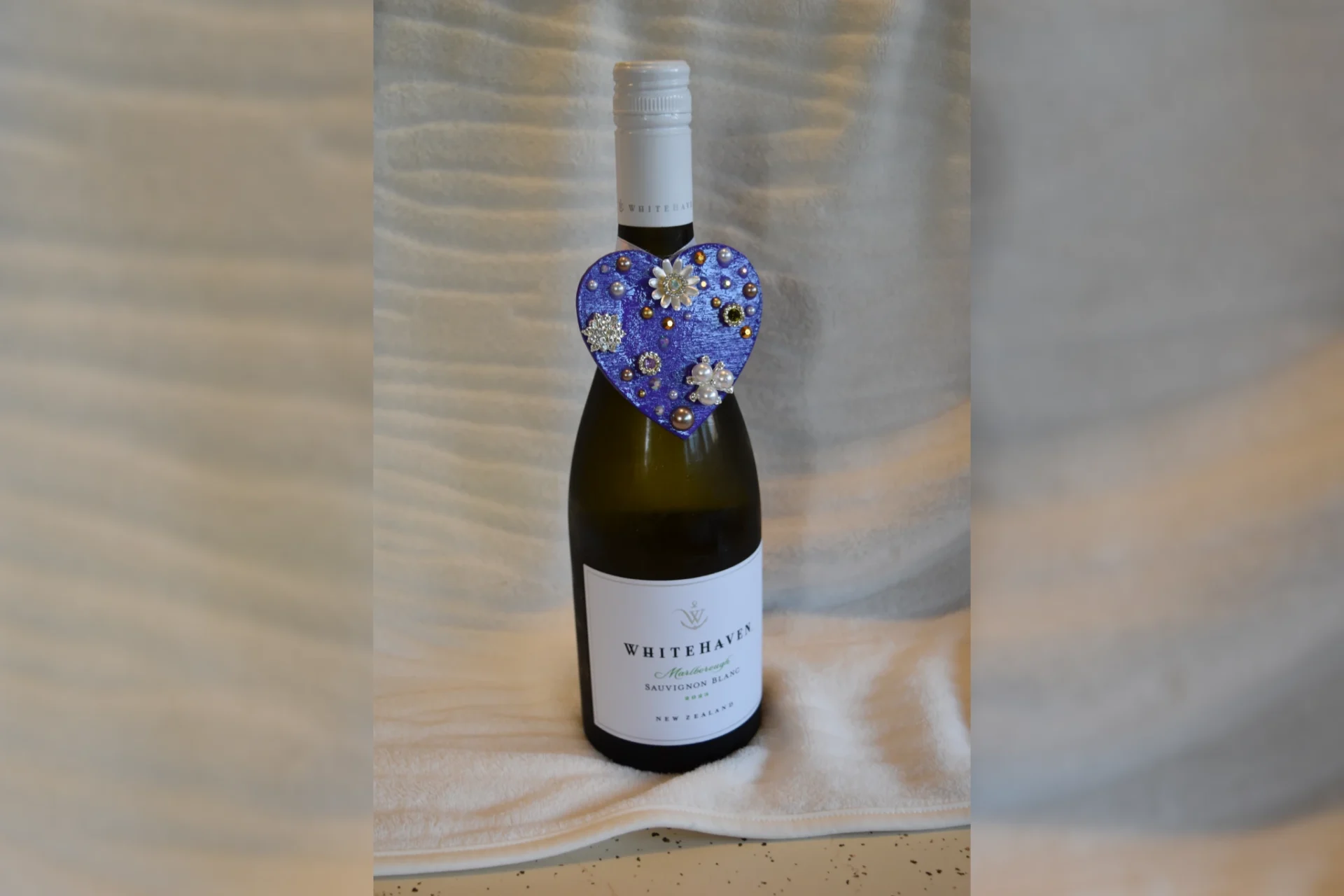 A bottle of wine with a heart shaped fabric tag.